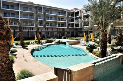 an apartment building with a swimming pool and palm trees at Royal Deluxe Platinum - Marrakech, Luxe Pool View in Marrakech