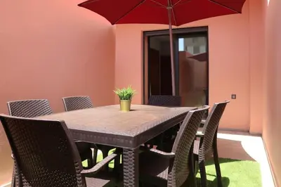 a wooden table with chairs and a red umbrella at Chic Hideaway - Marrakech Centre in Marrakech