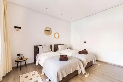 two beds in a bedroom with white walls and wooden floors at Loft Duplex Familial 200m2 Neuf - Centre Gueliz in Marrakech