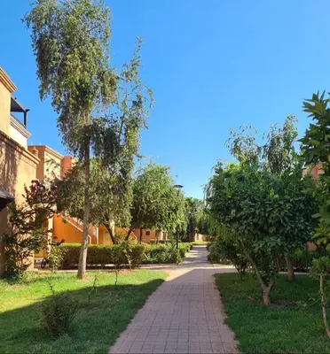 a walkway through a park with trees and grass at Atlas golf resort in Marrakech